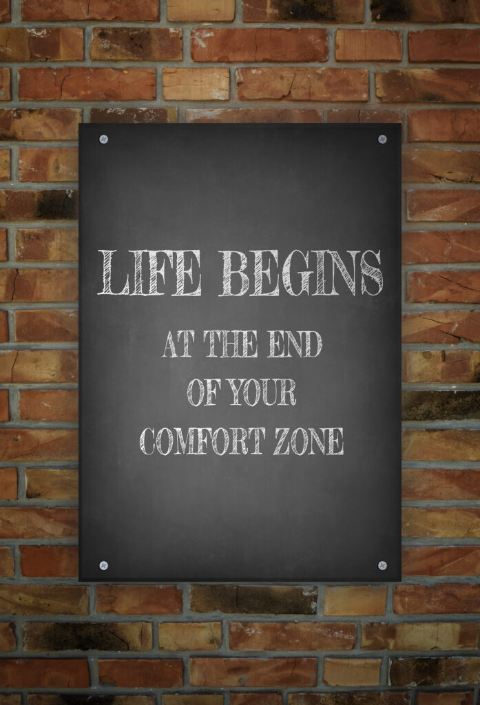 LIFE BEGINS AT THE END OF YOUR COMFORT ZONE hand drawn poster on brick wall