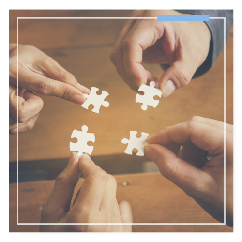 4 hands holding each holding a puzzle piece and they are reaching to connect them