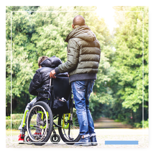 Man standing behind a person in a wheelchair ready to walk him