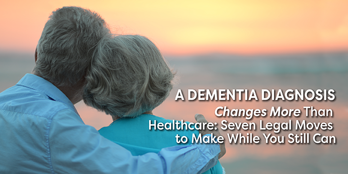 See the backside of a senior couple looking out at a beautiful sunset. Husband has his arm around the shoulder of his wife.