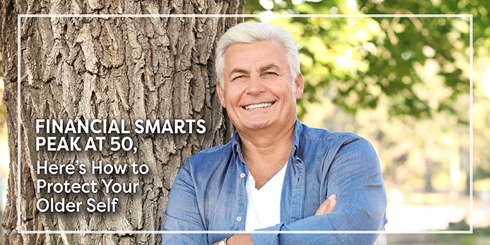 Mature man with his arms folded leaning on a tree in a park.