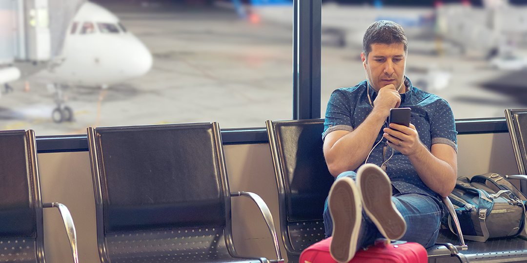 Person on their phone waiting for their plane at the gate - signifies the flexibility of estate planning via zoom